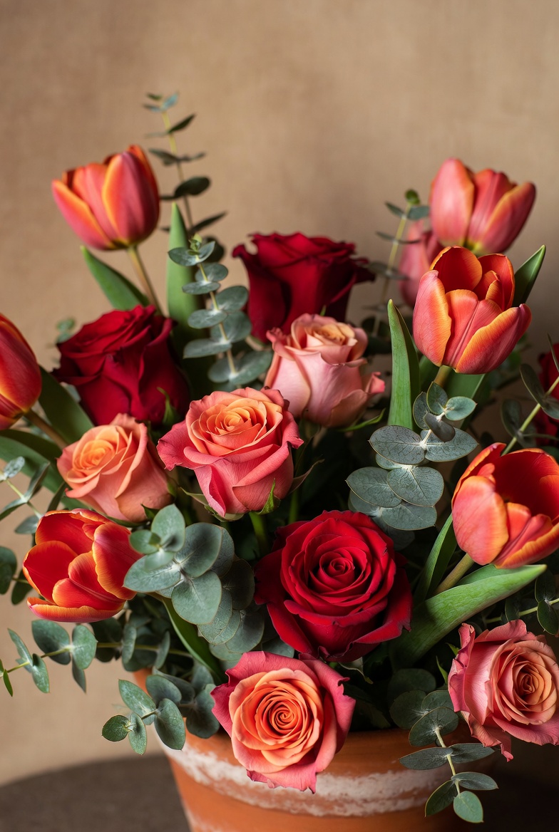 Boeket met tulpen, rozen en eucalyptus in terracotta, warm beige en zacht rood, strak maar natuurlijk geschikt rood oranje boeket met eucalyptus en tulpen